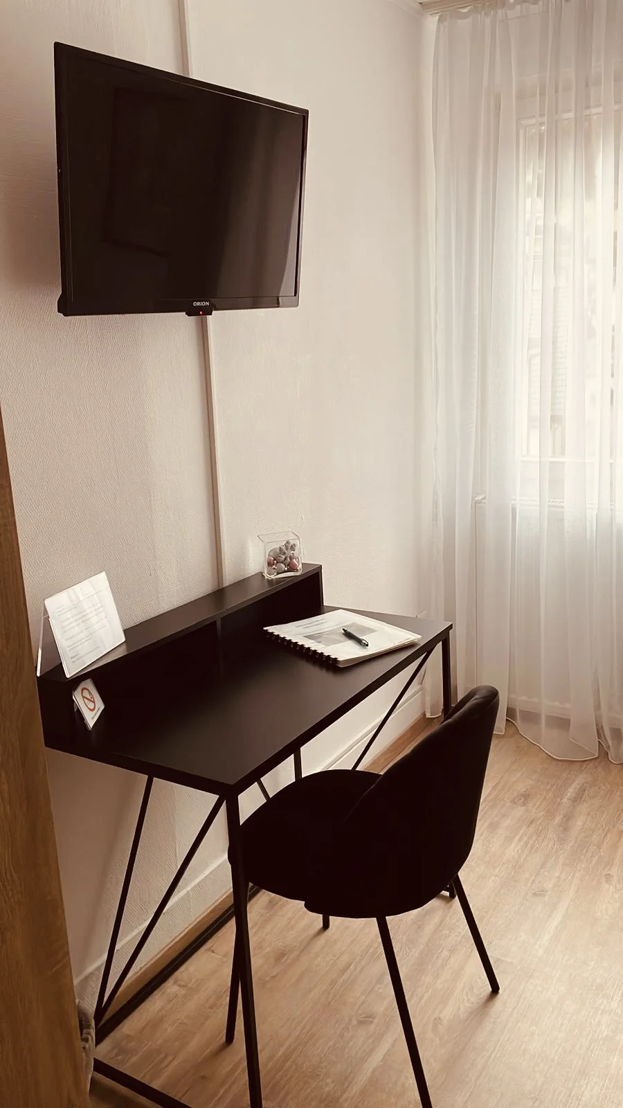 Schwarzer Schreibtisch und Stuhl und ein an der Wand montierter Fernseher