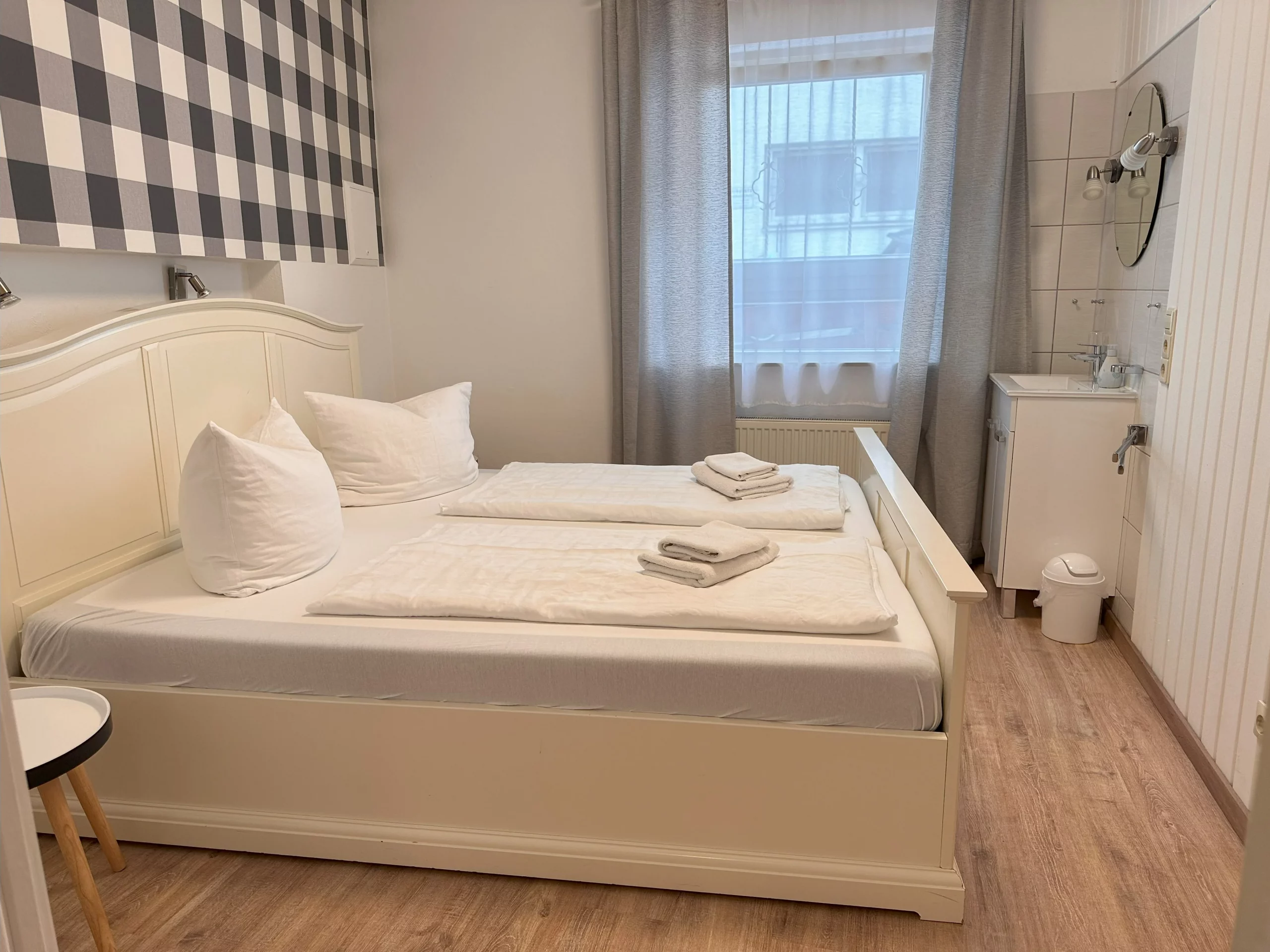 Weiß eingerichtetes Schlafzimmer mit kleinem Waschschrank und Spiegel