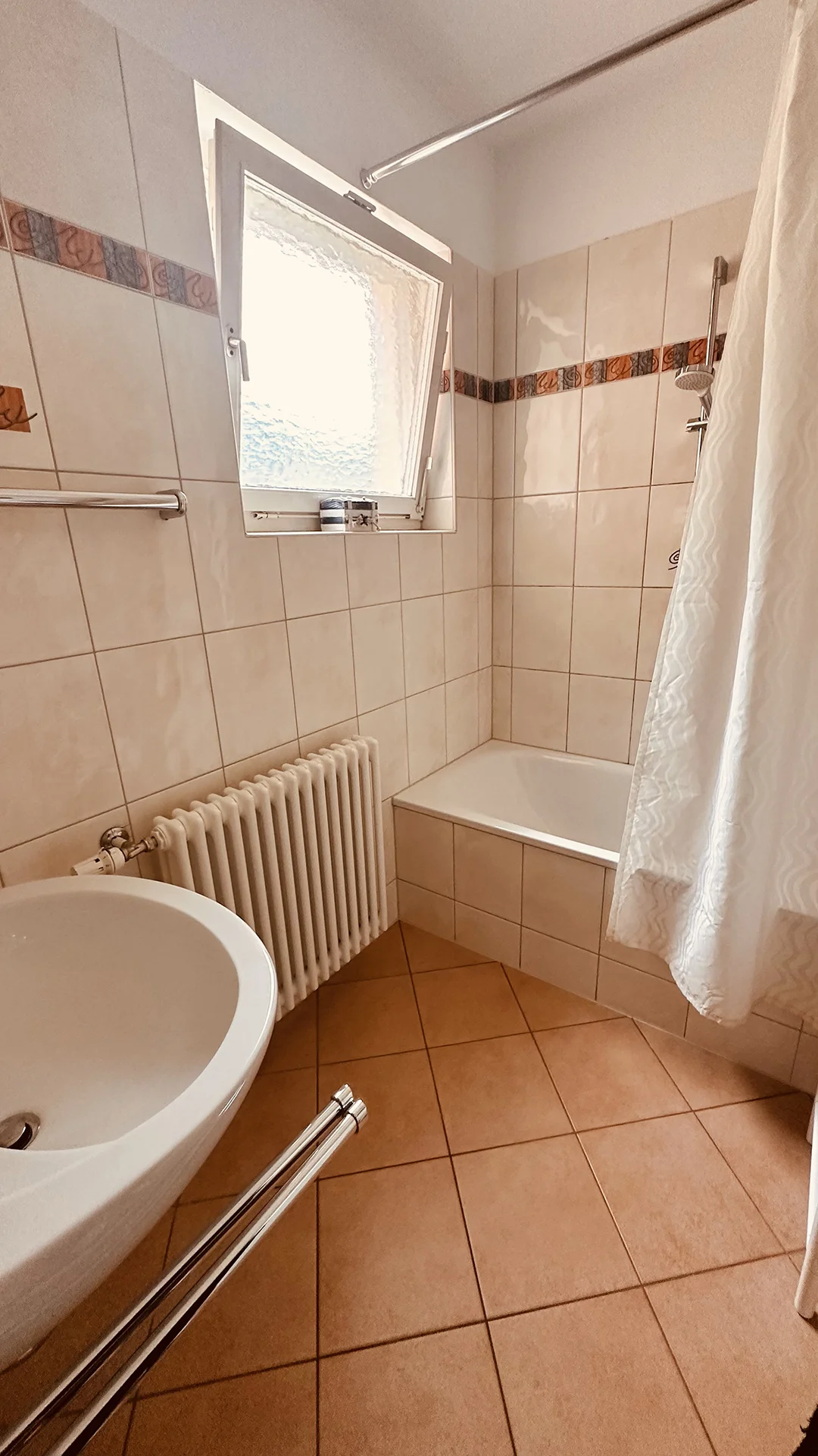 Ein Badezimmer mit beigen Fliesen und einer Badewanne