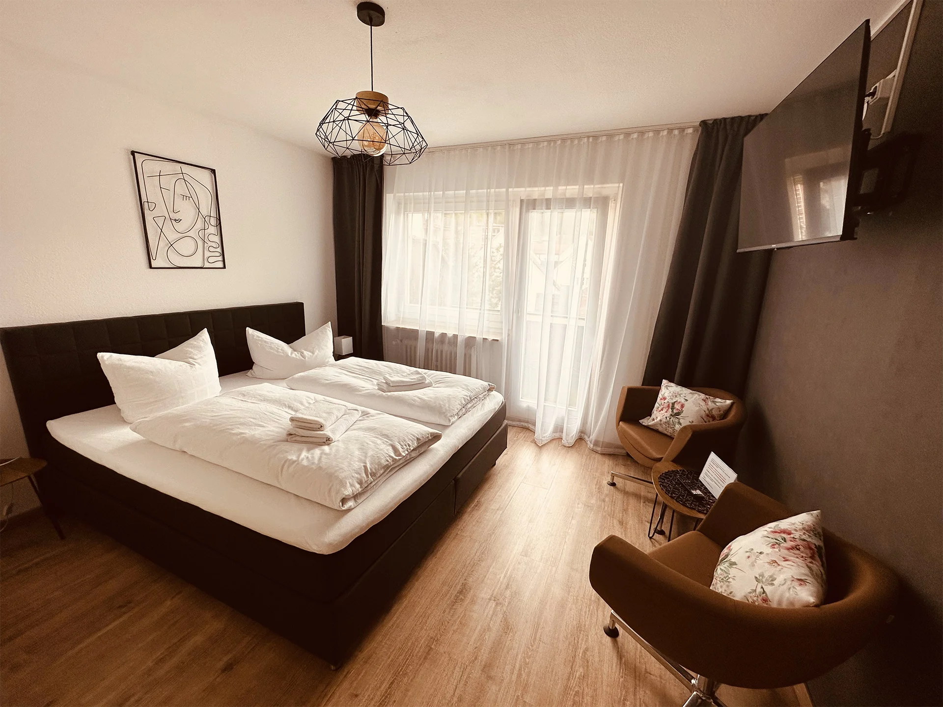 Ein Kaffeefarben eingerichtetes Schlafzimmer mit einem Doppelbett, Stühlen und einen Fernseher