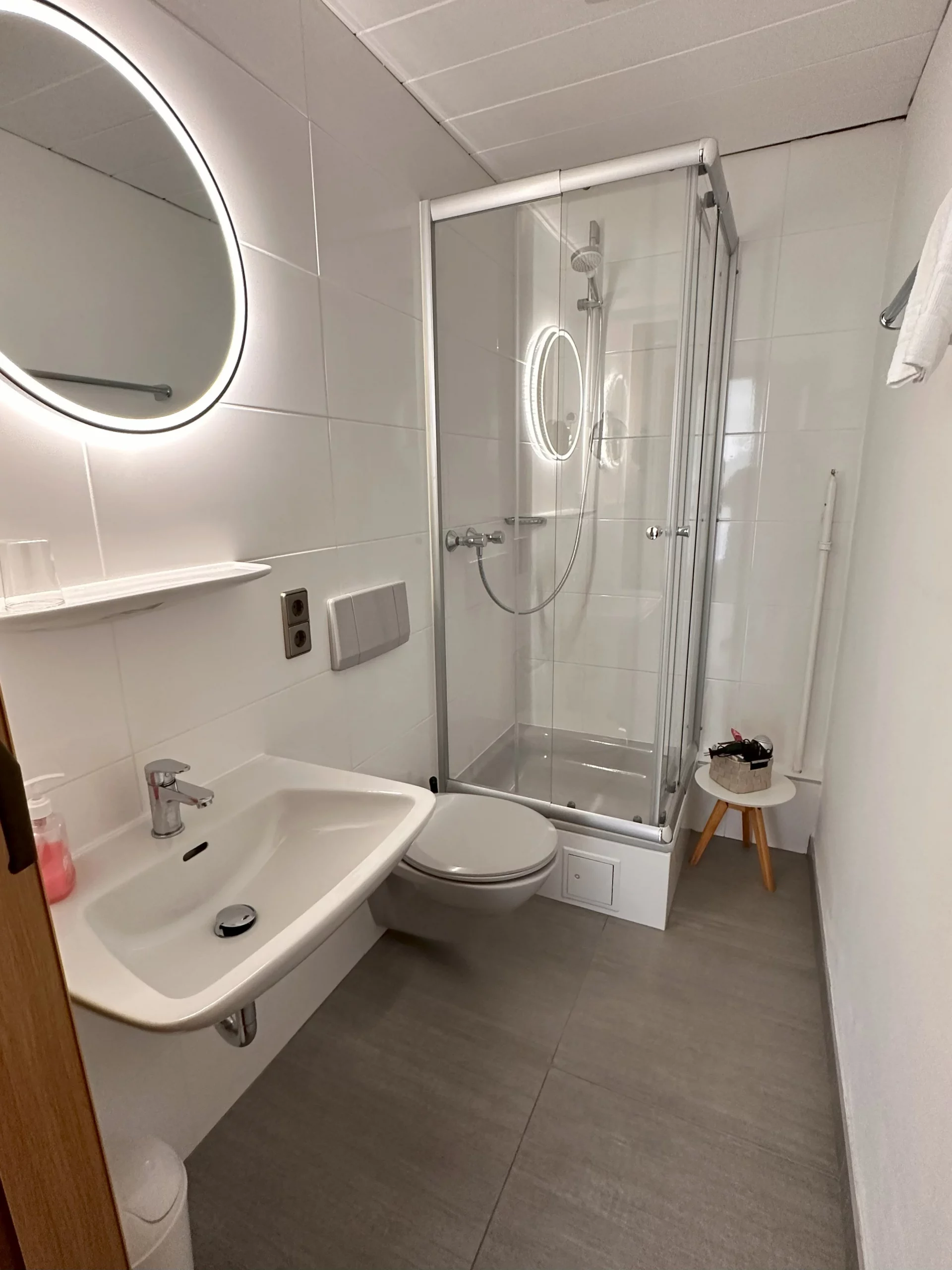 Badezimmer mit Duschkabine und beleuchtem Spiegel