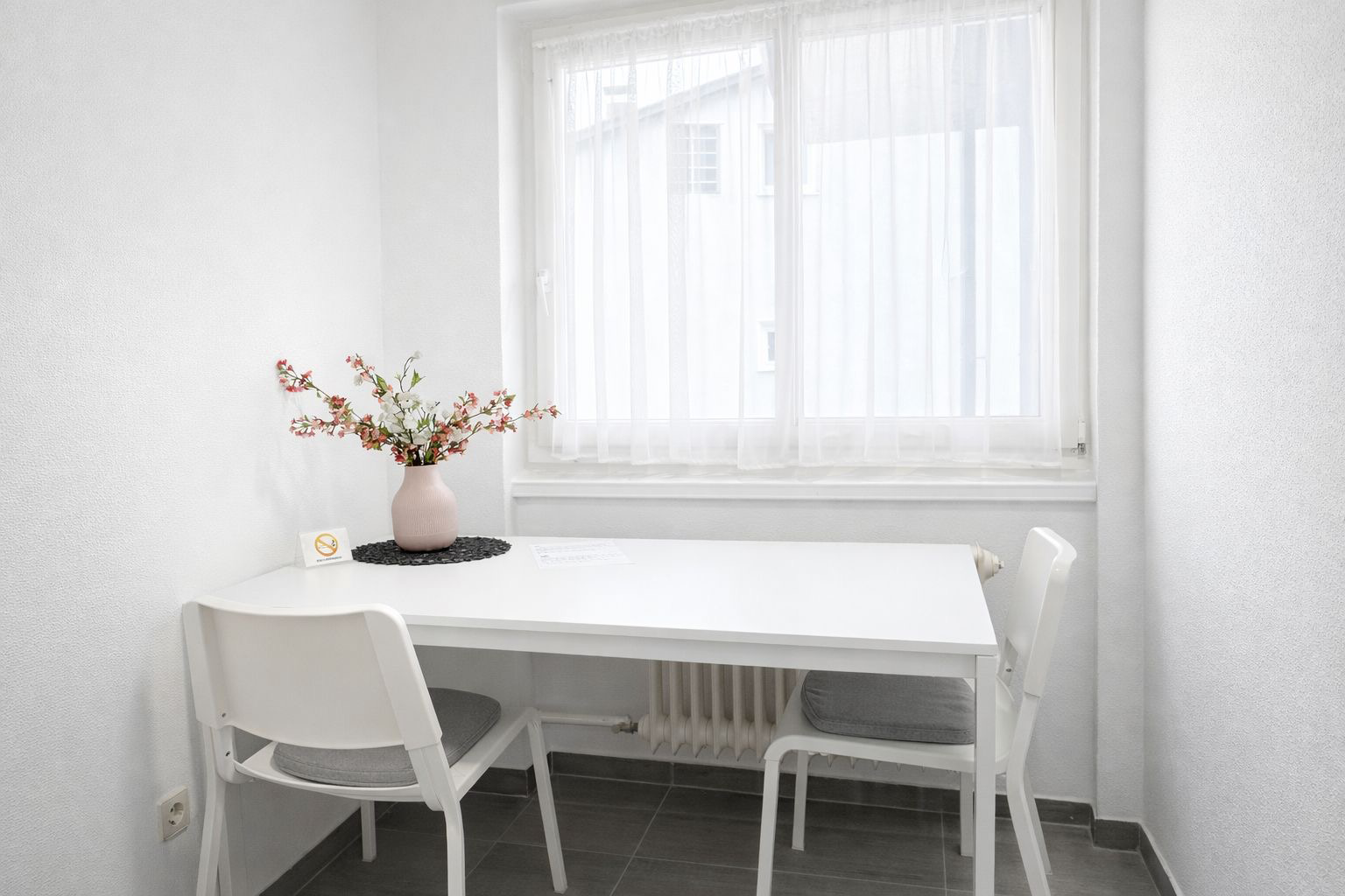 Ein weißer Tisch mit zwei herangeschobenen Stühlen