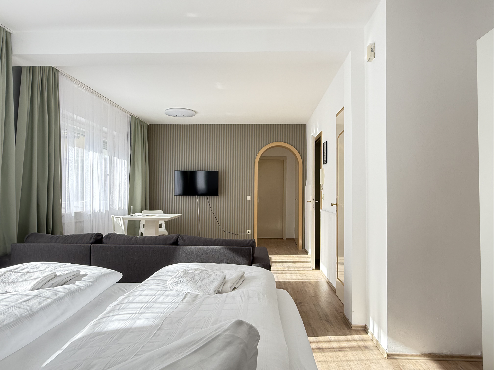 Ansicht Zimmer mit Türbogen , einem dunkelgrauen Schlafsofa und einem doppelbett