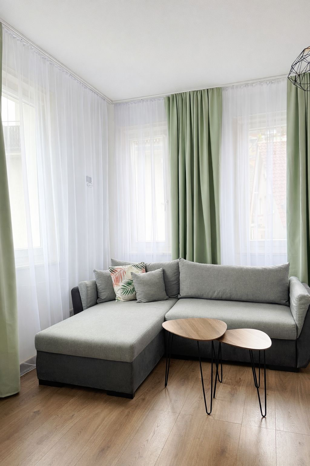 Ein grau/grünliches Sofa und weiße / olive Vorhänge