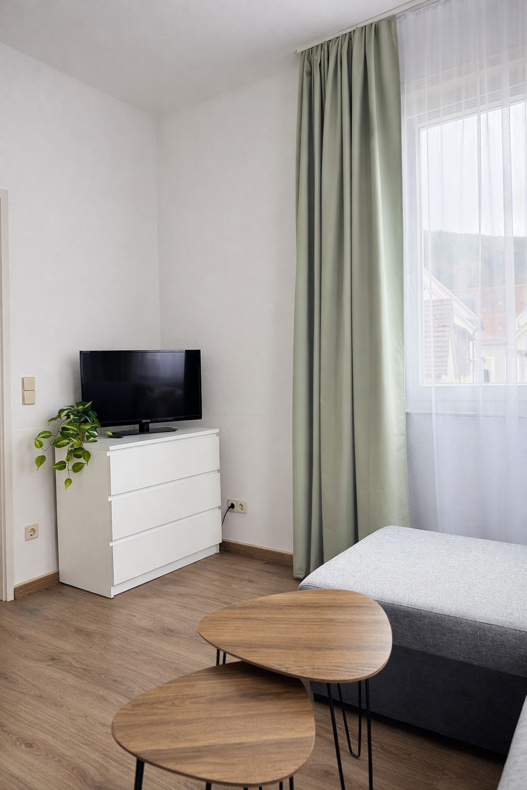 Ein Fernseher auf einem weißen Regal vor einem grauen Sofa